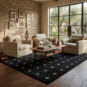 Può includere: Un tappeto nero caratterizzato da un motivo a griglia con accenti a punto croce bianchi, posizionato in un soggiorno con tre poltrone beige, un tavolino da caffè in legno e una lampada da terra in rame con paralume sferico bianco.