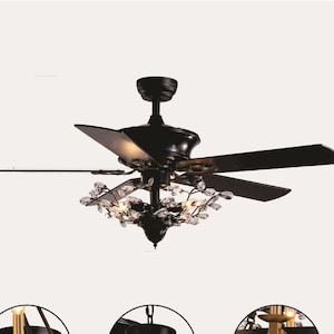 Könnte beinhalten: Ein schwarzer Deckenventilator mit vier Flügeln und einer dekorativen Leuchte. Die Leuchte hat Kristallakzente und kleine Lichter. Der Ventilator ist für den Innenbereich konzipiert und hat einen klassischen, eleganten Stil.
