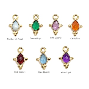 Könnte beinhalten: Eine Sammlung von Edelstein-Anhängern in verschiedenen Farben, darunter Weiß, Grün, Rosa, Orange, Rot, Blau und Lila. Jeder Anhänger hat einen tropfenförmigen Stein, der in einem goldfarbenen Metallrahmen gefasst ist. Der Text beschreibt jeden Stein: Mother of Pearl, Green Onyx, Pink Quartz, Carnelian, Red Garnet, Blue Quartz und Amethyst.