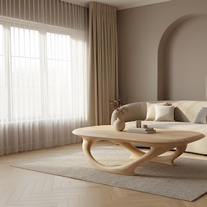 May include: A light-toned wooden coffee table with a smooth, oval-shaped top and a sculptural, open-frame base. The table features a natural wood grain finish and sits on a rectangular area rug in a room with beige curtains and a curved sofa.