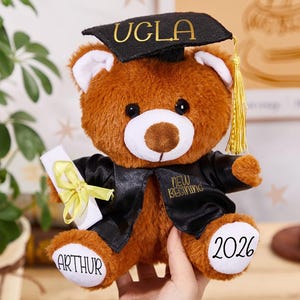 Puede incluir: Una taza de cerámica blanca con asa negra y el texto "But First, Coffee" en negrita negra. La taza está llena de un líquido oscuro, probablemente café, y se encuentra sobre una superficie clara.