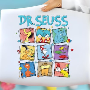 May include: White tote bag featuring the text "DR. SEUSS" in blue, with colorful square illustrations of Dr. Seuss characters. The bag is held by a person, with a blurred background of Easter eggs and flowers.