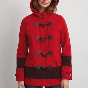 Könnte beinhalten: Ein roter Dufflecoat mit Kapuze, schwarzen Knebelverschlüssen und dunkelbraunen Akzenten an Ärmeln und Saum. Der Mantel hat ein klassisches Design, ideal für die kalte Jahreszeit.