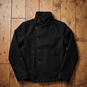 Könnte beinhalten: Eine schwarze Cabanjacke mit hohem Kragen und einem Knopfverschluss, einer zweireihigen Vorderseite mit vier sichtbaren Knöpfen, langen Ärmeln und zwei vertikalen Eingrifftaschen auf der Vorderseite. Die Jacke hat ein strukturiertes Design.