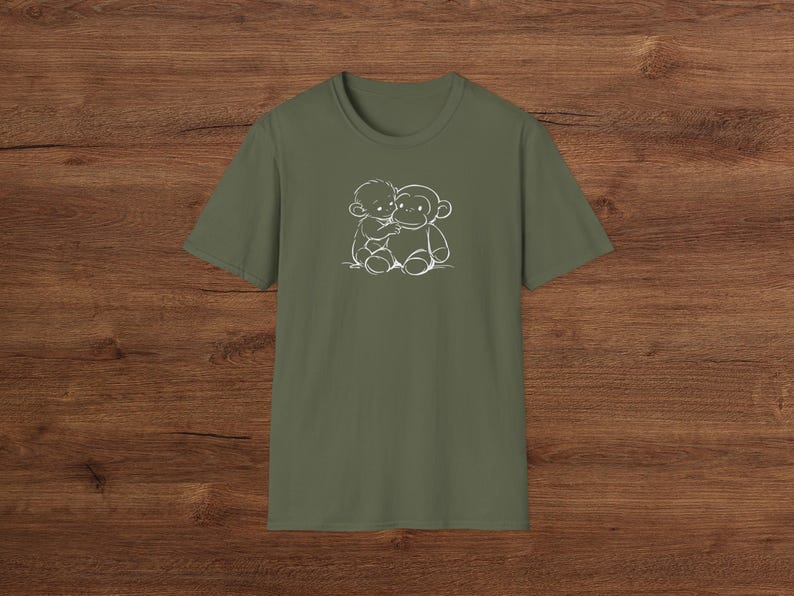May include: Olive green t-shirt with a white outline illustration of a child embracing a monkey. The design is on the front of the crew neck, short-sleeved shirt. The shirt is made of a soft fabric.
