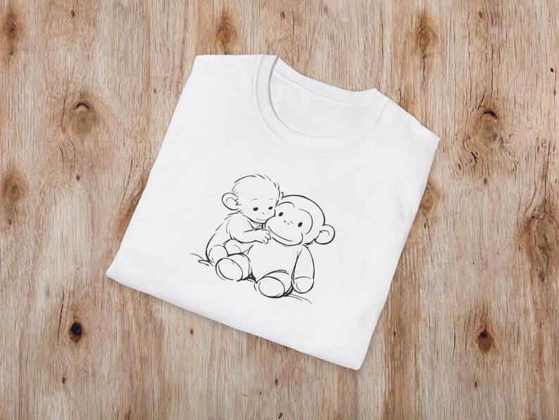 May include: White crew neck t-shirt with a black and white illustration of two monkeys. One monkey is sitting on top of the other. The t-shirt is made of a soft material and is folded on a wooden surface.