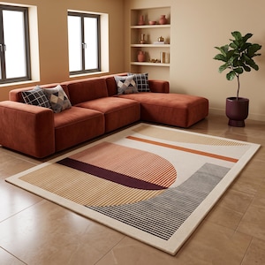 May include: A rectangular area rug featuring a geometric pattern with a large semi-circle, horizontal stripes, and solid blocks in shades of burnt orange, dark brown, and cream. The rug is placed on a tiled floor in front of a large rust-coloured sofa.