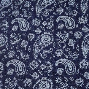 Może przedstawiać: Granatowa tkanina z białym wzorem paisley. Wzór obejmuje duże kształty paisley, elementy kwiatowe i motywy liści. Gęsty, szczegółowy wzór tworzy teksturowany wygląd.