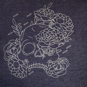 Peut inclure: Écusson en denim bleu foncé avec un motif de crâne floral blanc. Le crâne est orné de fleurs et de feuilles blanches, créant une image contrastée. Le motif est centré sur le tissu en denim.