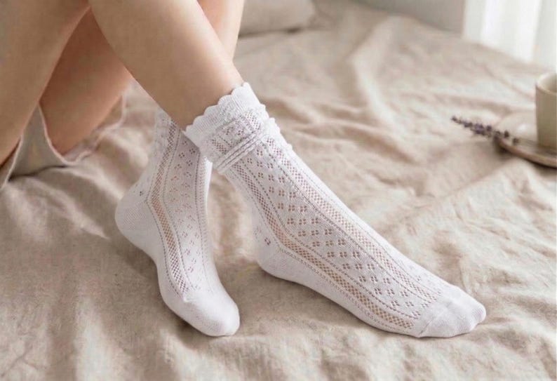 May include: White lace socks with a delicate openwork design. The socks feature a scalloped trim at the top and are knee-high. The socks are made of a soft, breathable material, perfect for adding a touch of elegance to any outfit.