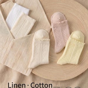 May include: An assortment of socks in various colors, including white, cream, light pink, and yellow. The socks are made of linen and cotton, with a delicate, skin-friendly texture. The image also includes text that reads "Linen &bull; Cotton" and "Delicate & Skin-friendly / Natural Antibacterial."