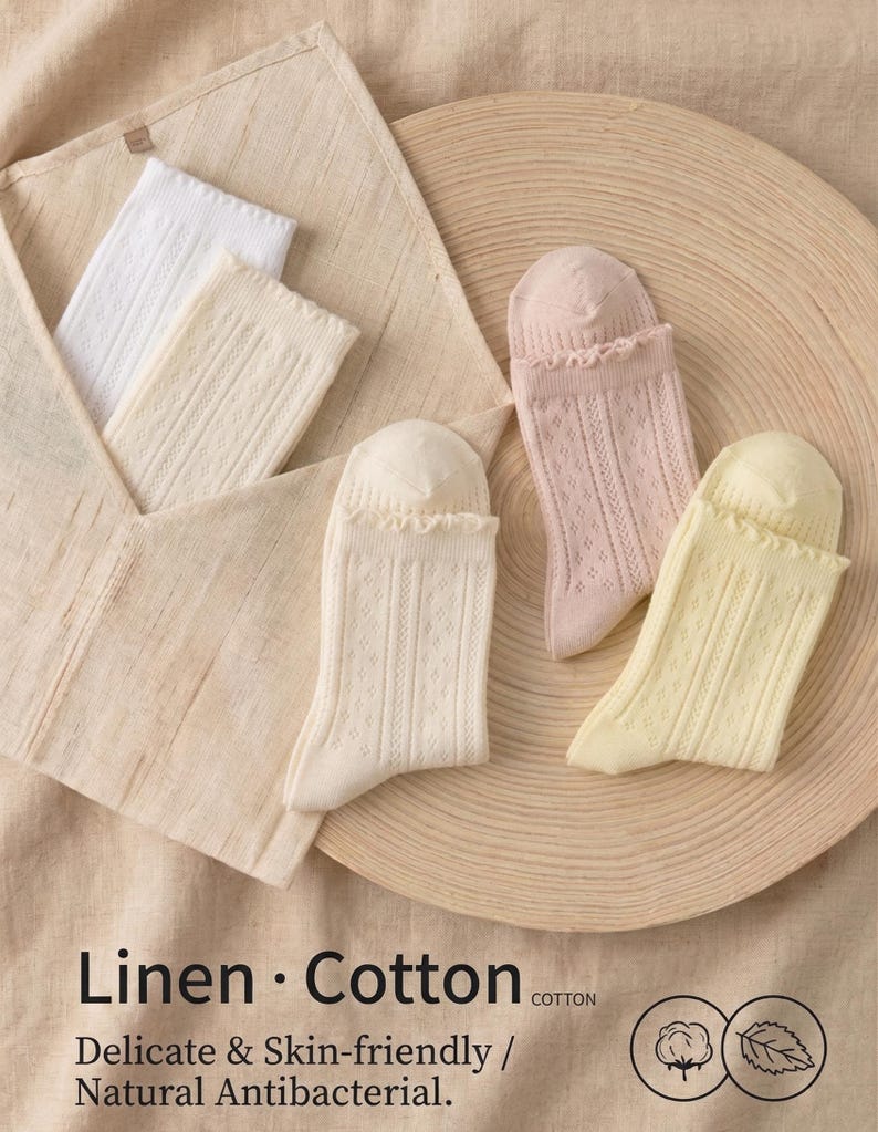 May include: An assortment of socks in various colors, including white, cream, light pink, and yellow. The socks are made of linen and cotton, with a delicate, skin-friendly texture. The image also includes text that reads "Linen &bull; Cotton" and "Delicate & Skin-friendly / Natural Antibacterial."