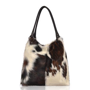 Puede incluir: Un bolso tote de piel de vaca con un asa de cuero negro. El bolso presenta una mezcla de pelo marr&oacute;n, negro y blanco. El bolso est&aacute; dise&ntilde;ado con una parte superior grande y abierta y un asa larga.