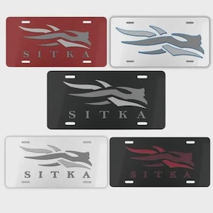 May include: Five license plates in various colors: red, white, black, and dark grey. Each plate features a stylized graphic and the word "SITKA" in capital letters. The plates have four mounting holes.