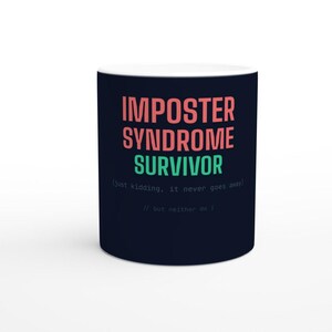 Könnte beinhalten: Eine dunkel marineblaue Keramiktasse mit dem Text IMPOSTER SYNDROME SURVIVOR in Lachsrosa und Mintgrün. Darunter steht in kleinerer, hellgrauer Schrift der Text (just kidding, it never goes away) sowie // but neither do I.