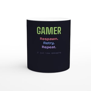 Puede incluir: Una taza de cerámica negra con el texto GAMER en verde lima, seguido de las palabras Respawn en rosa, Retry en azul y Repeat en morado, con el texto // just like debugging en una fuente gris pequeña en la parte inferior de la taza.