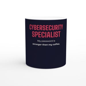 Könnte beinhalten: Ein dunkelblauer Keramikbecher mit dem Text CYBERSECURITY SPECIALIST in fetten rosa Buchstaben, gefolgt von dem weißen Text My password is stronger than my coffee. Der Becher hat eine glatte Oberfläche und einen weißen Innenrand oben.