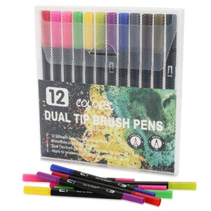 Op de afbeelding: Een set van 12 dual-tip penseelstiften in een doorzichtige plastic hoes. De verpakking bevat de tekst 12 colors dual tip brush pens met een aquarelachtergrond. Elke stift heeft een zwarte behuizing met gekleurde doppen aan beide uiteinden.