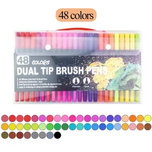 Op de afbeelding: Een doorzichtige plastic etui met 48 dual-tip brushpennen met verschillende gekleurde doppen. Het label vermeldt 48 COLORS DUAL TIP BRUSH PENS, met tips van 1-2 mm en 0,4 mm. Onder de etui zijn 48 cirkelvormige kleurstaaltjes in rijen gerangschikt.