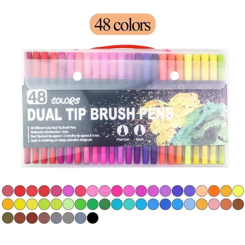 Op de afbeelding: Een doorzichtige plastic etui met 48 dual-tip brushpennen met verschillende gekleurde doppen. Het label vermeldt 48 COLORS DUAL TIP BRUSH PENS, met tips van 1-2 mm en 0,4 mm. Onder de etui zijn 48 cirkelvormige kleurstaaltjes in rijen gerangschikt.