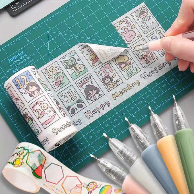 May include: A roll of decorative washi tape featuring a grid of numbered calendar dates, cartoon characters, and the text "Sunday Happy Monday Tuesday". A second roll shows hexagonal frames and food illustrations. Five gel pens are arranged in a row.