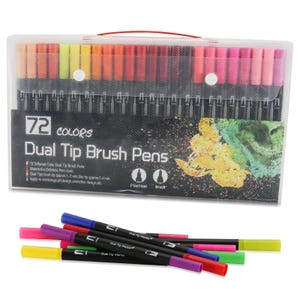 Op de afbeelding: Een set van 72 dual-tip penseelstiften in een doorzichtige plastic draagtas met een rood handvat. De tas bevat de tekst 72 COLORS Dual Tip Brush Pens. Verschillende stiften met zwarte behuizing en gekleurde doppen liggen voor de tas.