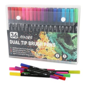 Op de afbeelding: Een set van 36 dual-tip penseelstiften in een doorzichtige plastic etui. De verpakking bevat de tekst 36 COLORS DUAL TIP BRUSH PENS en toont een aquarel-stijl afbeelding. Verschillende stiften met gekleurde doppen liggen voor de etui.