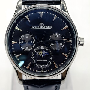 May include: A luxury wristwatch with a dark blue face and silver accents. The watch features multiple sub-dials, a moon phase indicator, and the text "JAEGER-LECOULTRE AUTOMATIQUE SWISS MADE". The watch has a black leather band.