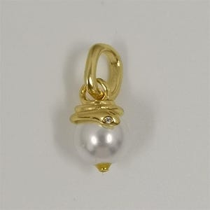 Könnte beinhalten: Ein Goldanhänger mit einer weißen, kugelförmigen Perle, die an einer polierten Goldöse hängt. Die Oberseite der Perle ist von einem goldenen Schlangenmotiv mit einem winzigen, klaren Stein als Auge umgeben und schließt mit einer Goldspitze ab.