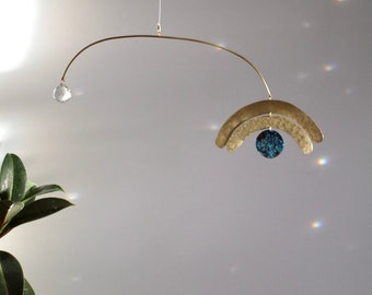 Atrapasueños de luz con escultura cinética hecha a mano en latón para interiores modernos con cristal para captar la luz.