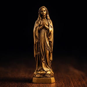 Peut inclure: Une statue dorée d'une femme en robe fluide, les mains jointes en prière. La statue a une expression sereine et un chapelet. La base est de forme géométrique simple. Le fond est sombre.