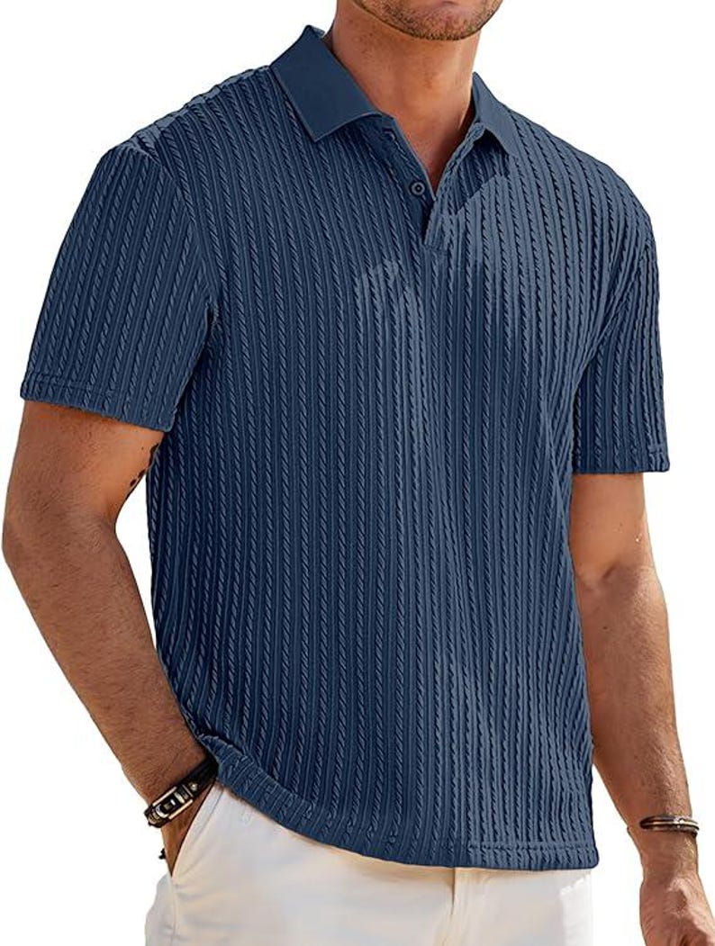 May include: A short-sleeved navy blue polo shirt featuring a vertical ribbed texture throughout the fabric. The shirt includes a classic collar and a buttoned placket at the neckline, providing a structured look with a consistent dark blue color.