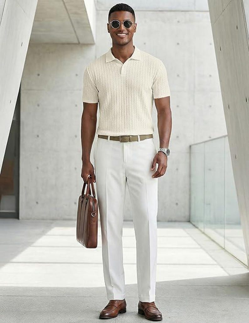 May include: A short-sleeved cream-colored polo shirt with a textured knit pattern, paired with crisp white trousers, a tan leather belt, brown leather loafers, and a brown leather briefcase. The outfit is accessorized with round sunglasses and a watch.
