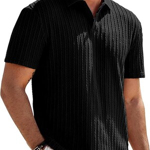 May include: A black short-sleeved polo shirt featuring a vertical ribbed texture throughout the fabric. The garment has a classic collar and a buttonless placket design, providing a clean and uniform appearance across the front and sleeves.