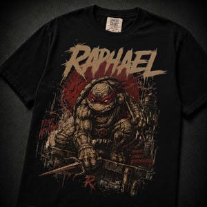 May include: A black t-shirt featuring a graphic of the character Raphael from Teenage Mutant Ninja Turtles. The design includes the text "RAPHAEL" at the top, "FEAR NOTHING" on the left, and "HONOR LOYALTY BROTHERHOOD" on the right in red and tan.