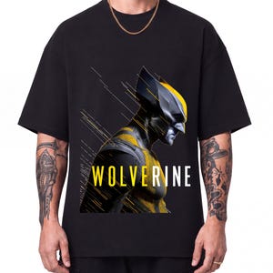 May include: A black short-sleeved t-shirt featuring a graphic print of the character Wolverine in profile. The design includes yellow and black armour details, motion lines, and the word WOLVERINE printed in yellow and white capital letters.