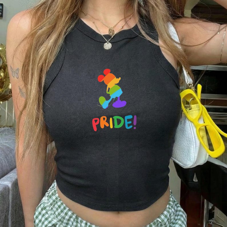 May include: Black crop top with a rainbow Mickey Mouse graphic and the word "PRIDE!" in rainbow colors. The tank top is sleeveless and has a round neckline. The design celebrates LGBTQ+ pride.