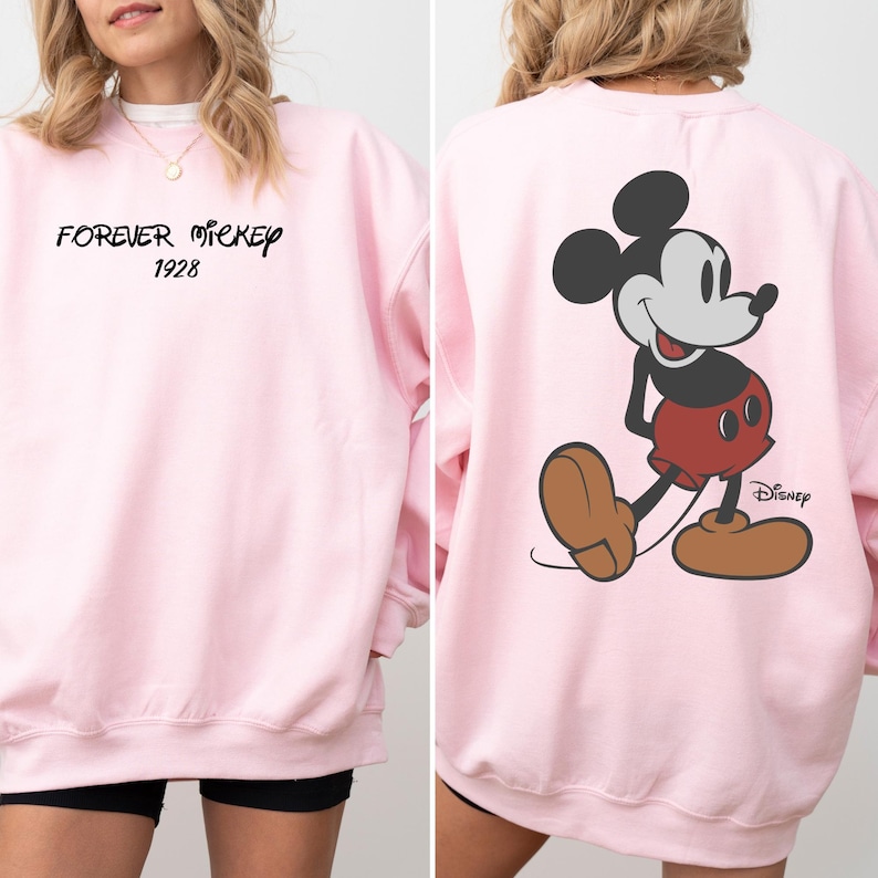 Puede incluir: Sudadera rosa claro con el texto "FOREVER MICKEY 1928" en la parte delantera. La parte trasera presenta un gr&aacute;fico de Mickey Mouse y el logotipo de Disney.