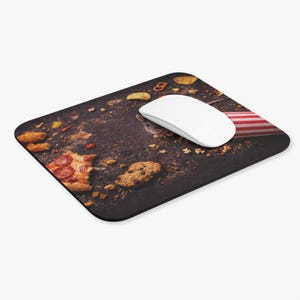 Könnte beinhalten: Ein rechteckiges Mauspad mit einer dunklen, strukturierten Oberfläche, die mit Essenskrümeln, einem Pizzastück und einer weißen Computermaus übersät ist. Eine kleine Maus lugt hinter der Maus hervor. Eine kleine amerikanische Flagge ist sichtbar.