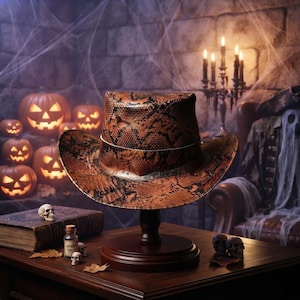 May include: A cowboy hat featuring a brown and black snakeskin pattern, displayed on a dark wooden stand. The hat has a structured crown and a wide, curved brim, showcasing a detailed reptilian texture across the entire surface of the material.