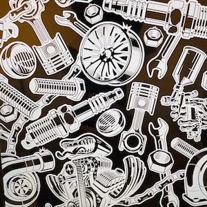 May include: A black and white sticker sheet featuring various automotive-themed illustrations. The design includes wrenches, pistons, spark plugs, nuts, bolts, and a stylized wheel. The overall theme is related to car repair and mechanics.
