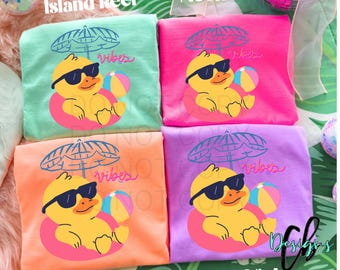 May include: Four colorful t-shirts, each folded and displaying a unique design. The shirts are in shades of green, pink, orange, and purple. Each shirt features a yellow duck wearing sunglasses and a beach ball, with the word "vibes" and an umbrella graphic.