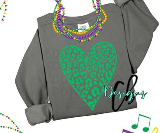 May include: A gray sweatshirt with a green leopard print heart design. The sweatshirt has rolled-up sleeves and is adorned with Mardi Gras beads. The image also includes musical notes and the text "Cb Designs".