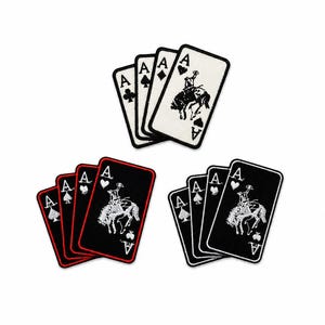 May include: Three sets of embroidered patches shaped like playing cards. One set features white cards with black details, while the other two sets feature black cards with white details and red or white borders, all depicting an ace and a bucking bronco.