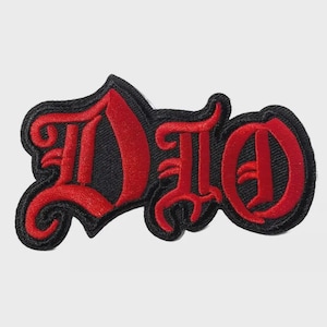 May include: Embroidered patch featuring the word "DIO" in a bold, gothic font. The letters are a vibrant red, outlined with black thread, and set against a black background. This patch is likely designed for clothing or accessories.