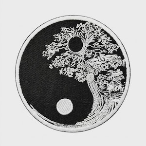 May include: A circular embroidered patch featuring a black and white yin-yang symbol. The design incorporates a detailed white tree silhouette that spans across the black and white sections, with a solid white circle in the black field.