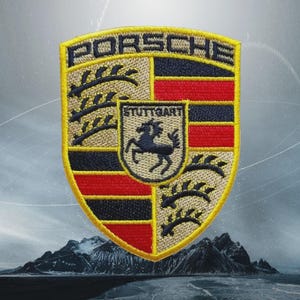 May include: Embroidered Porsche shield patch with the word "PORSCHE" at the top. The patch features a black horse in the center, with red, black, and tan sections. The word "STUTTGART" is also visible.