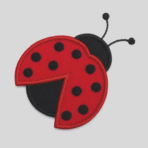 May include: A ladybird-shaped embroidered patch featuring a bright red wing section with black circular spots. The patch has a black circular base, a black head section, and two thin black antennae extending from the top of the head.