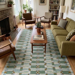 May include: A rectangular area rug featuring a geometric pattern in shades of light blue, sage green, and mustard yellow. The design consists of repeating block and stripe motifs arranged in a grid, covering the floor beneath a wooden coffee table.