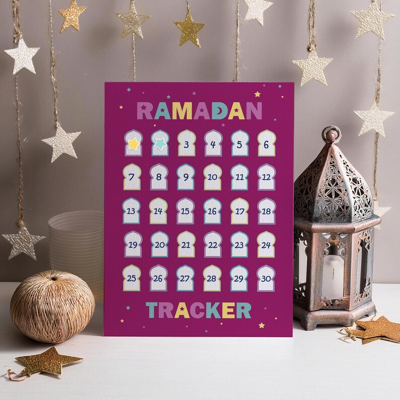 May include: A purple Ramadan Tracker poster with colorful text and numbers. The word "RAMADAN" is at the top, and "TRACKER" is at the bottom. The numbers 1-30 are arranged in a grid, with decorative star accents.